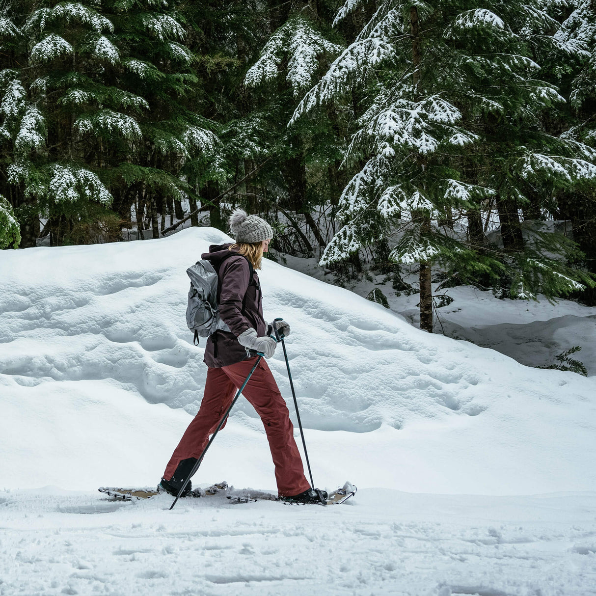 Hiker walking in snow wearing Quicksilver snowshoes on winter trail