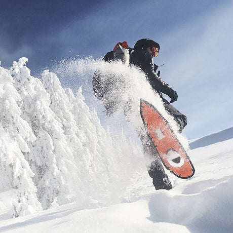 Hiker wearing Tundra 33 snowshoes walking through deep snow in the woods