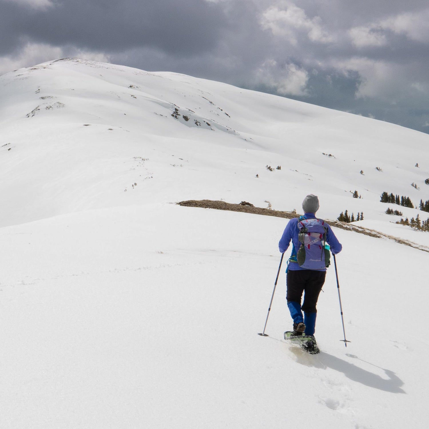 Female hiker snowshoeing uphill with Elite 25 snowshoes