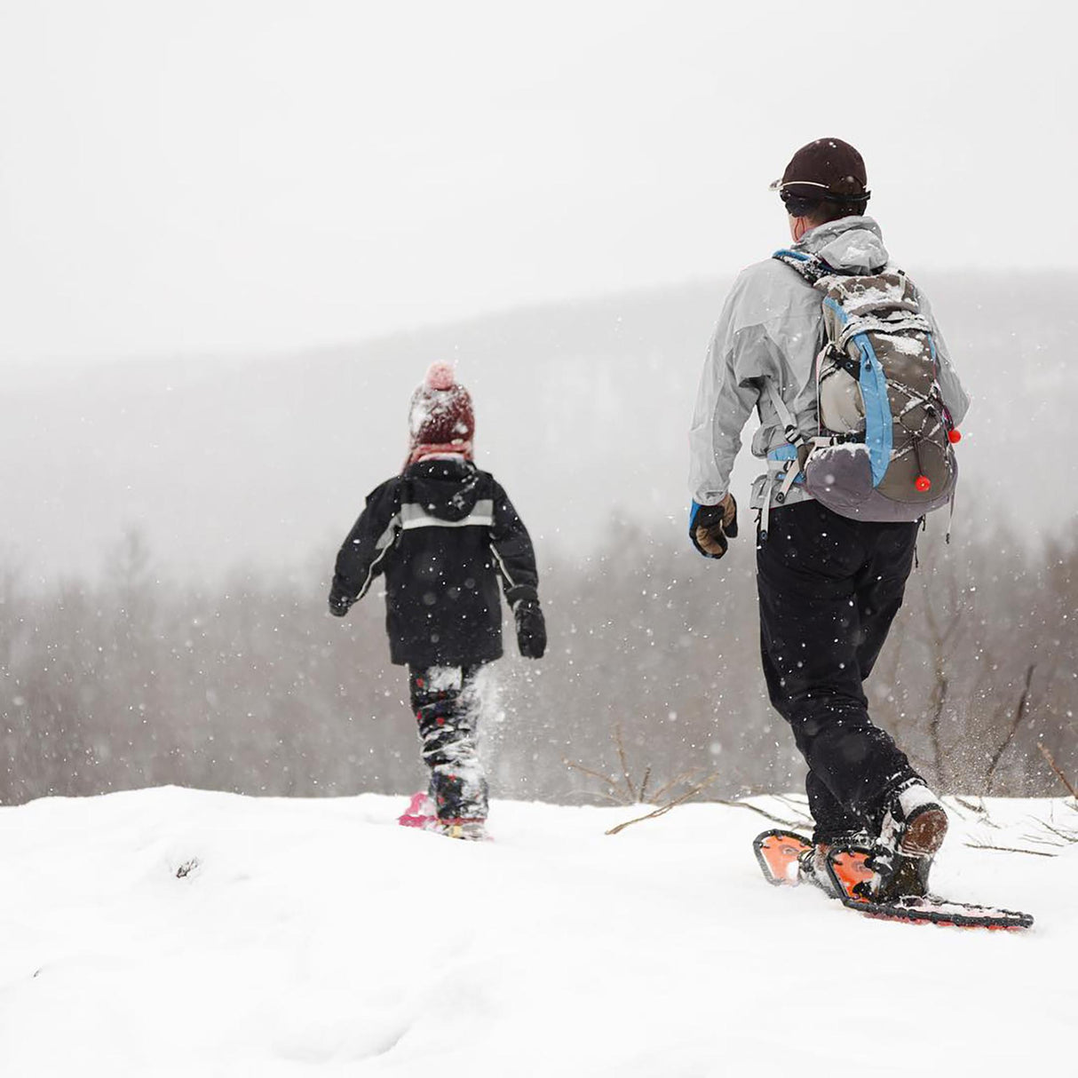 Winter hiker using Backpacker 25β33 snowshoes on a snow-covered trail