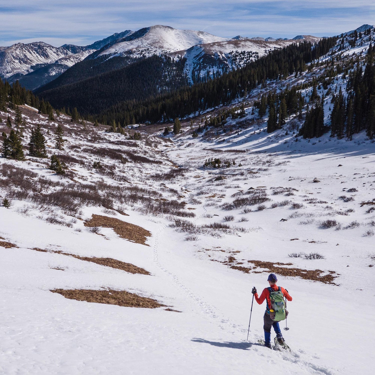 Woman trekking in mountain snow wearing Elite 25 snowshoes