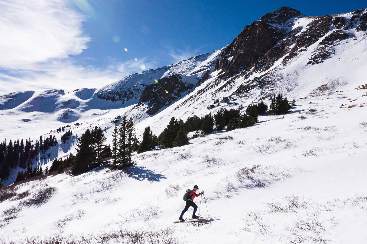 Athlete racing uphill in snow wearing Elite Race ultralight snowshoes