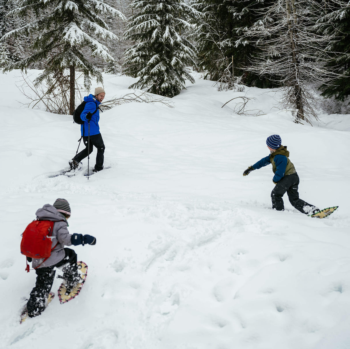 Child walking in snow wearing youth snowshoes on a winter trail