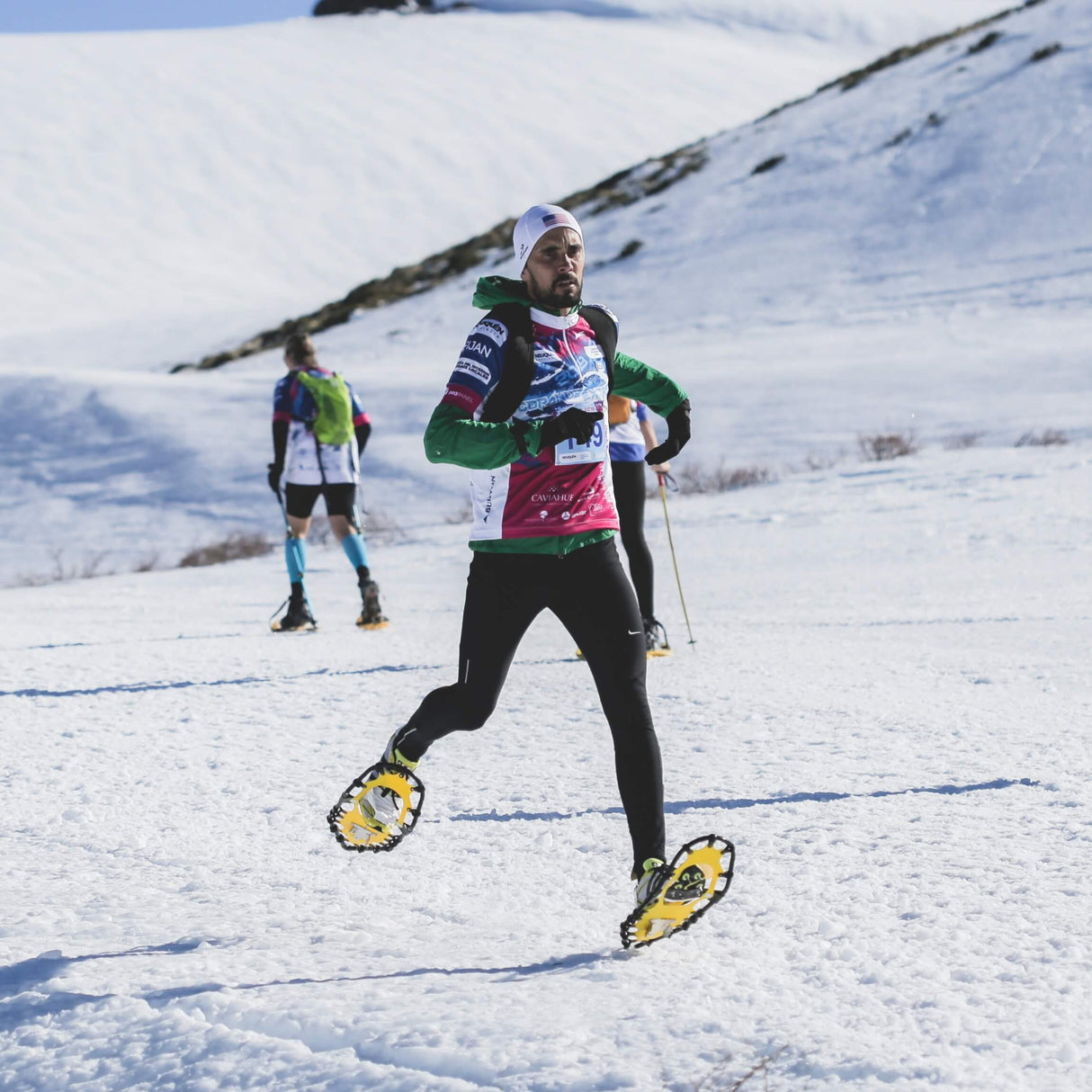 Group of athletes racing in snowshoe competition wearing race snowshoes
