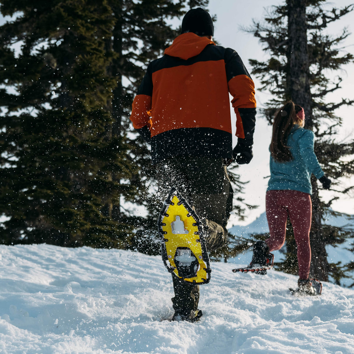 Runner wearing yellow race snowshoes on snowy trail during competition