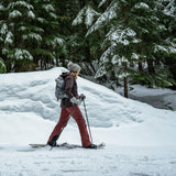 Hiker walking in snow wearing Quicksilver snowshoes on winter trail