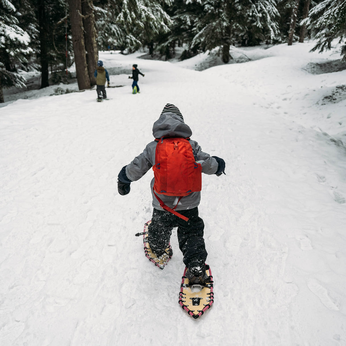 Young girl using youth snowshoes in deep snow, winter adventure scene