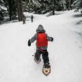 Young girl using youth snowshoes in deep snow, winter adventure scene