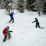 Child walking in snow wearing youth snowshoes on a winter trail